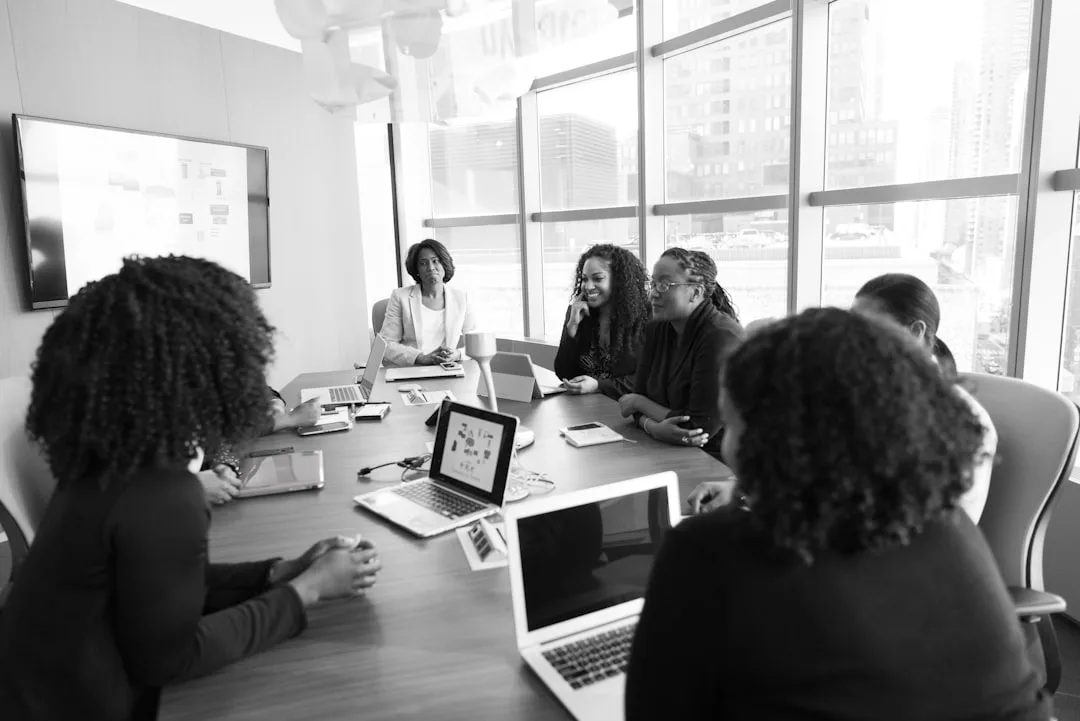 Pessoas sentadas ao redor de mesa de reunião em ambiente corporativo com luz natural