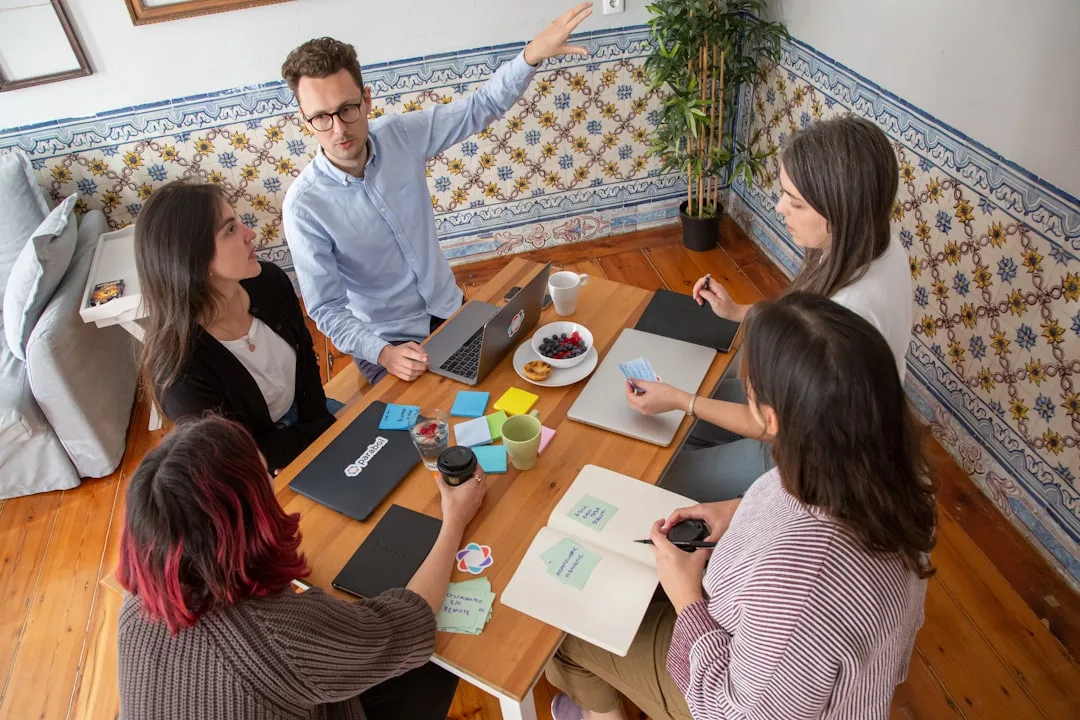 Grupo de pessoas sentadas ao redor de mesa de madeira em reunião colaborativa